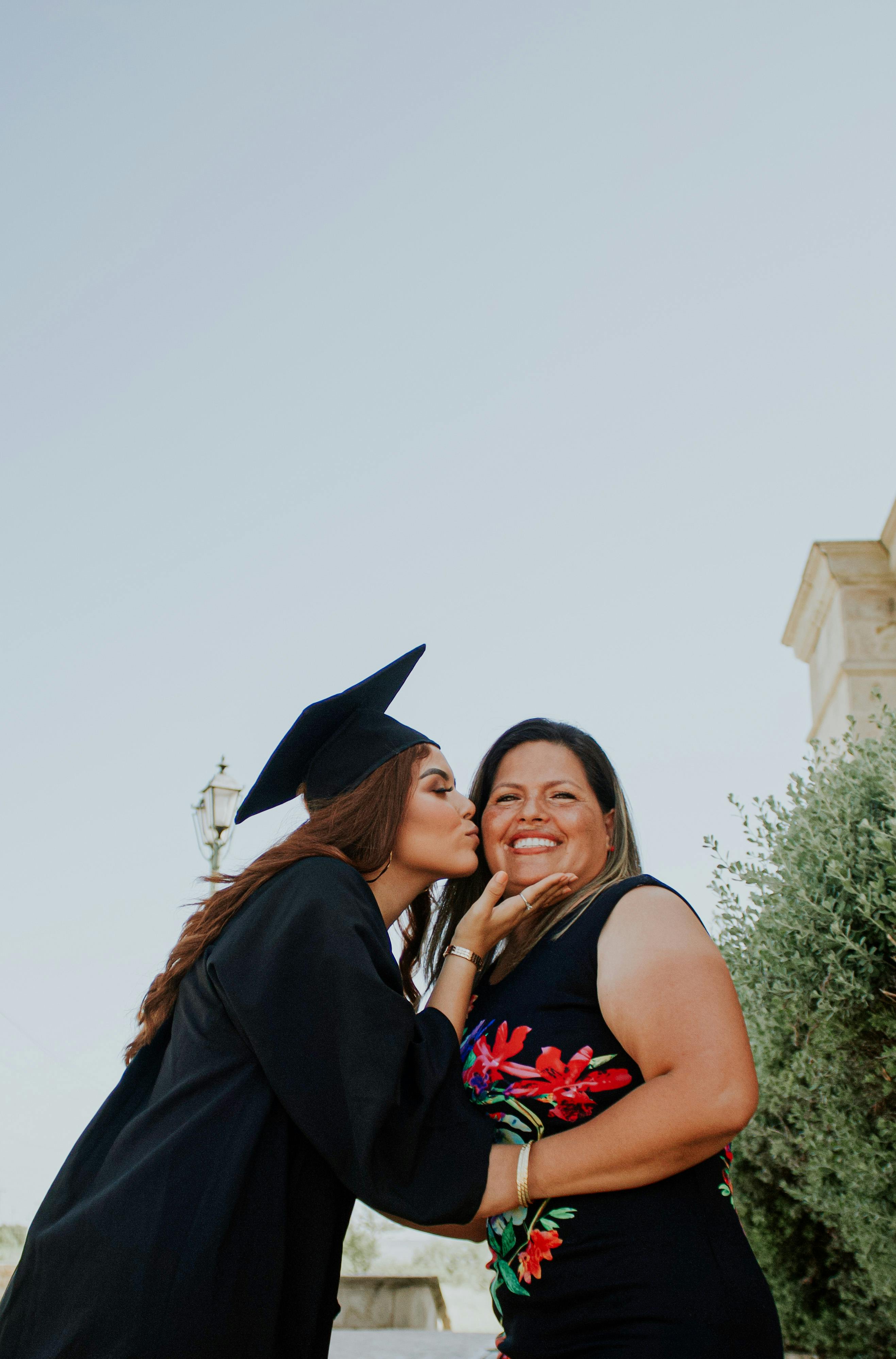 female graduate kissing smiling mother