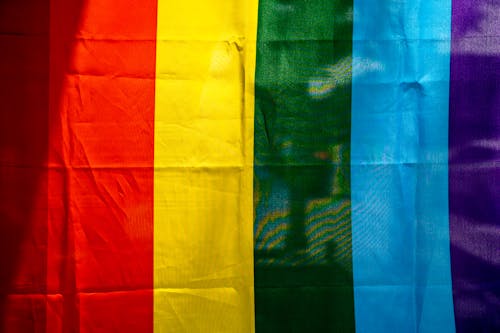 Background of multicolored rainbow flag with stripe ornament made of textile with creased surface in daytime
