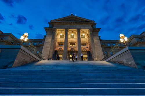 Free From below of aged classic house facade with shiny lights and staircase under blue cloudy sky in evening Stock Photo