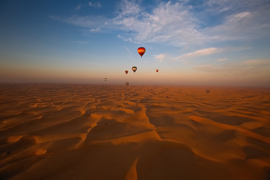 Free Hot Air Balloon Flying over Brown Sand Stock Photo