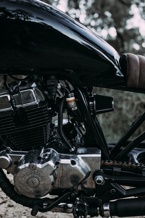 Closeup of modern shiny black metal motorcycle with soft saddle and big fuel tank on blurred background