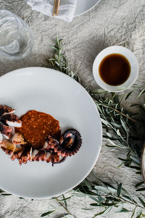 Free Top view of delicious cooked cut octopus tentacle on plate place on table near bown with soy sauce and empty glass Stock Photo