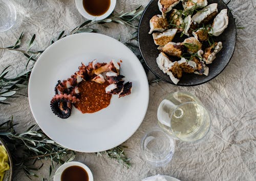 Free Top view of table served with palatable Asian dishes of octopus tentacle and gyozas dumplings with wine and soy sauce Stock Photo