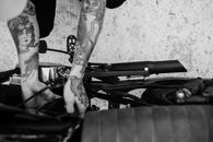 Tattooed biker fixing engine of motorcycle