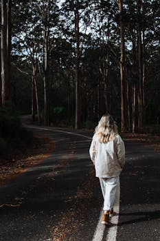 秋日，一名女子在宁静的林间小路上漫步，拥抱孤独与自然