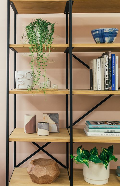 Free Various creative decorative elements and potted plants placed on wooden shelves near stack of books in modern apartment Stock Photo