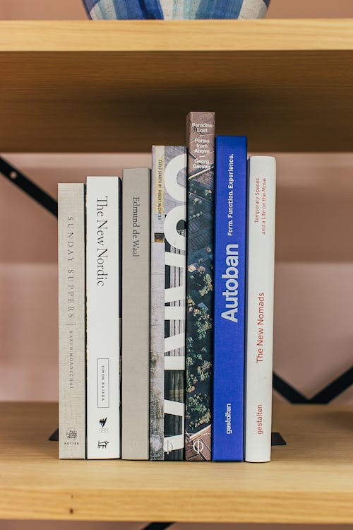 Stack of books placed on wooden shelf