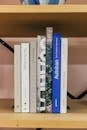Stack of books placed on wooden shelf