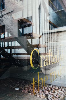 Modern staircase reflected on glass with decorative text, rainy day ambiance.