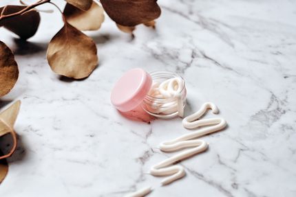 Open cream jar with a swatch on marble — Vie Studio on Pexels