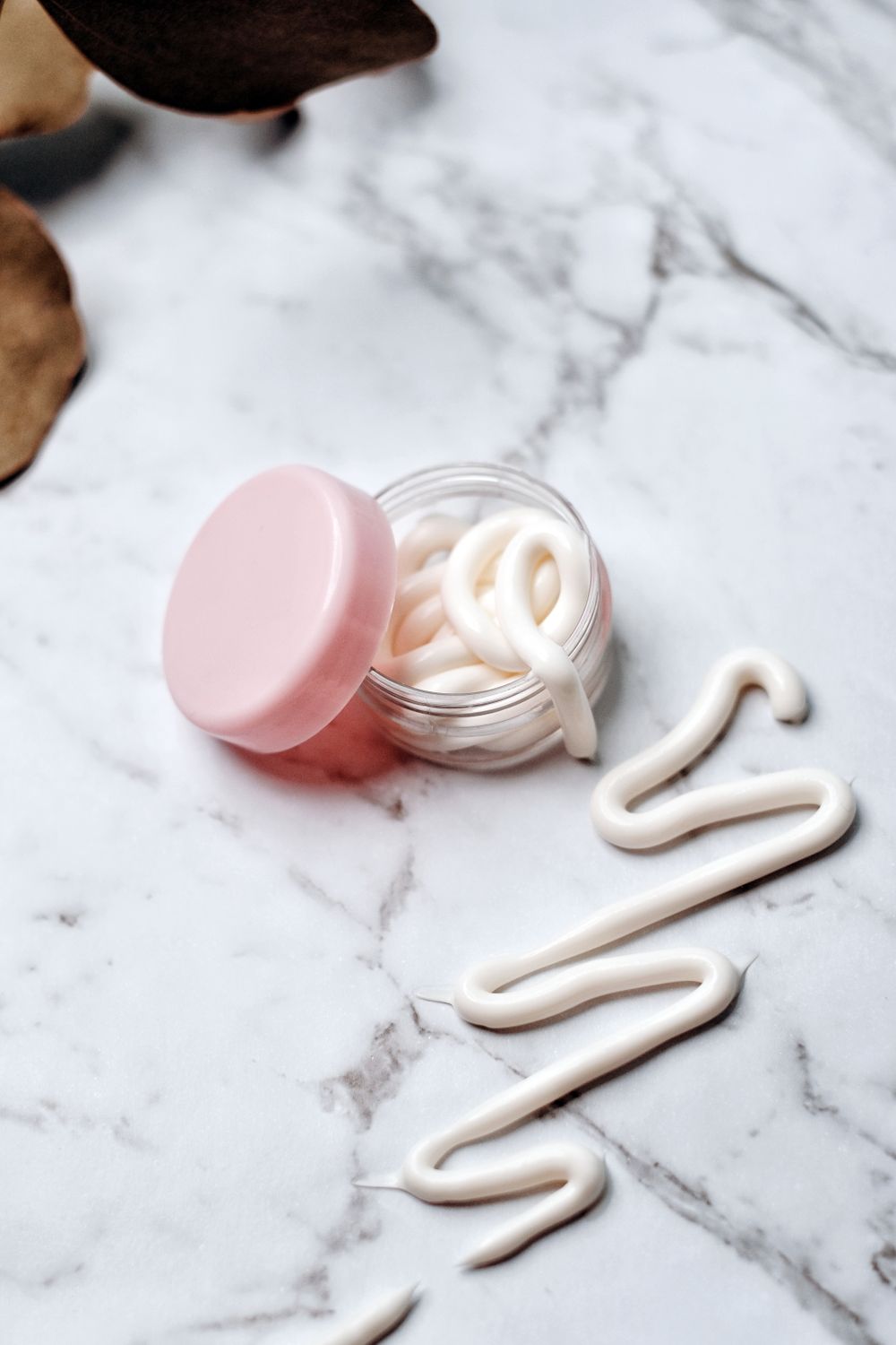 Unbranded cream jar and cream swirl on marble