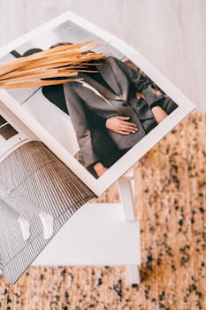 An elegant interior setup featuring a magazine with fashion imagery and dried plants on a textured mat.