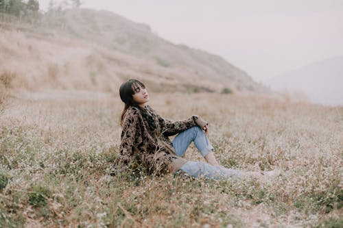 Free Photo of a Woman in a Black and Brown Sweater Sitting on the Grass Stock Photo