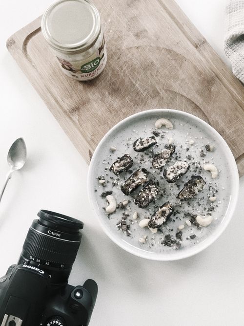 Free A bowl of nutritious cereal with cashews and chocolate, captured next to a DSLR camera and cutting board. Stock Photo