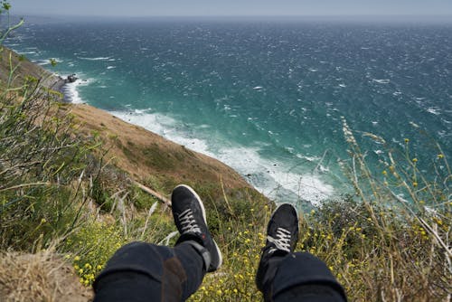 Photo of a Person's Legs Near the Sea