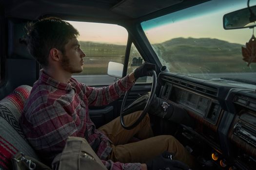 A young man drives a vintage car, showcasing scenic views and interior details.