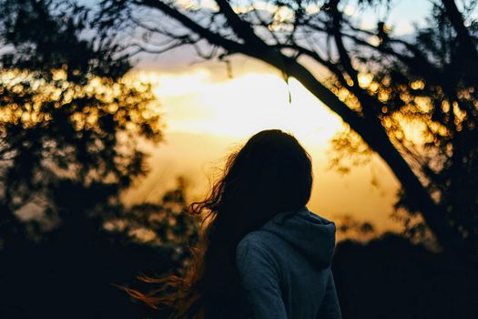 Silhouette of a woman with long hair at sunset under trees in Canberra, Australia.