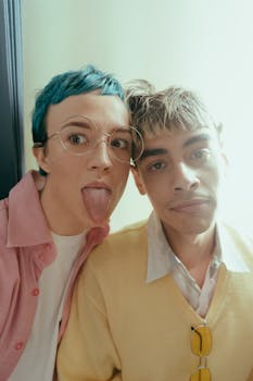 Two trendy teenagers in a photobooth, showing playful expressions with colorful styles.