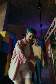 两名时尚青少年在室内街机里玩得开心，气氛活泼