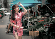 在一个阳光明媚的日子里，一位穿着粉色连衣裙的年轻女子漫步于热闹的街头市场