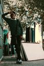 Full length of African American teenager leaning on metal gate while standing with legs crossed and pondering on trouble