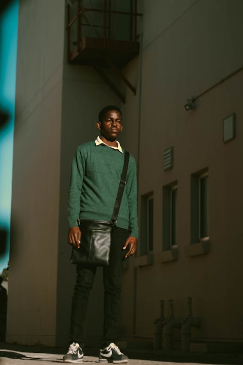 Serious black teen boy standing alone on street