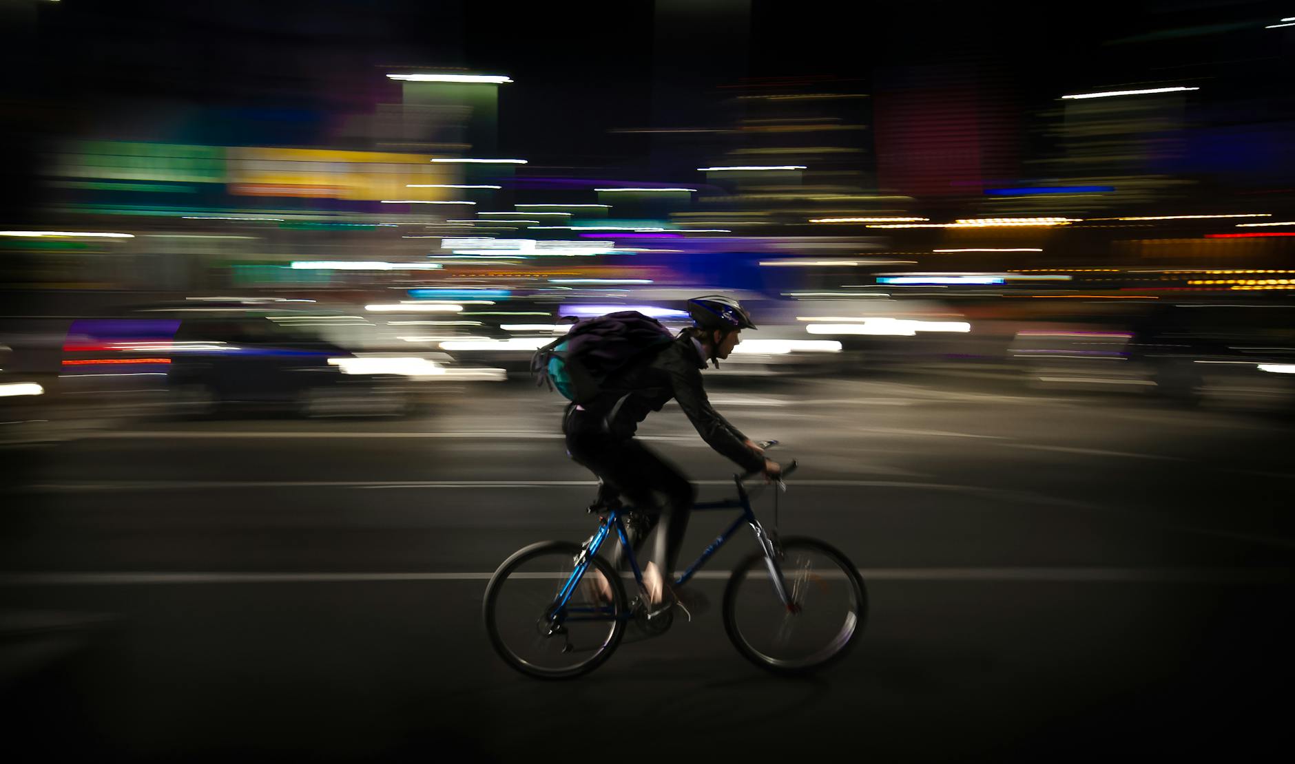Nighttime cyclist speeding through city with blurred motion. Urban energy captured in motion.