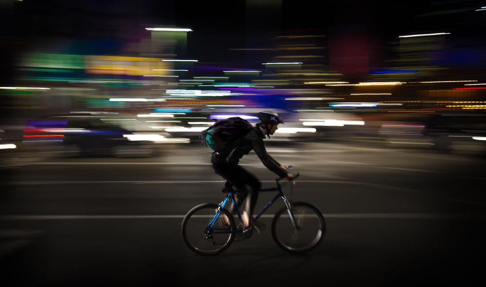 Radfahrer fährt nachts durch die Stadt, Bewegungsunschärfe