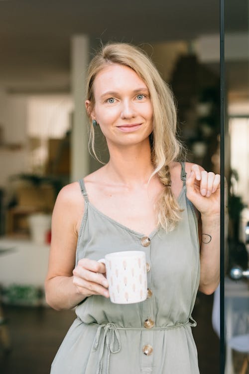 Free A Woman Smiling while Holding a Ceramic Mug Stock Photo
