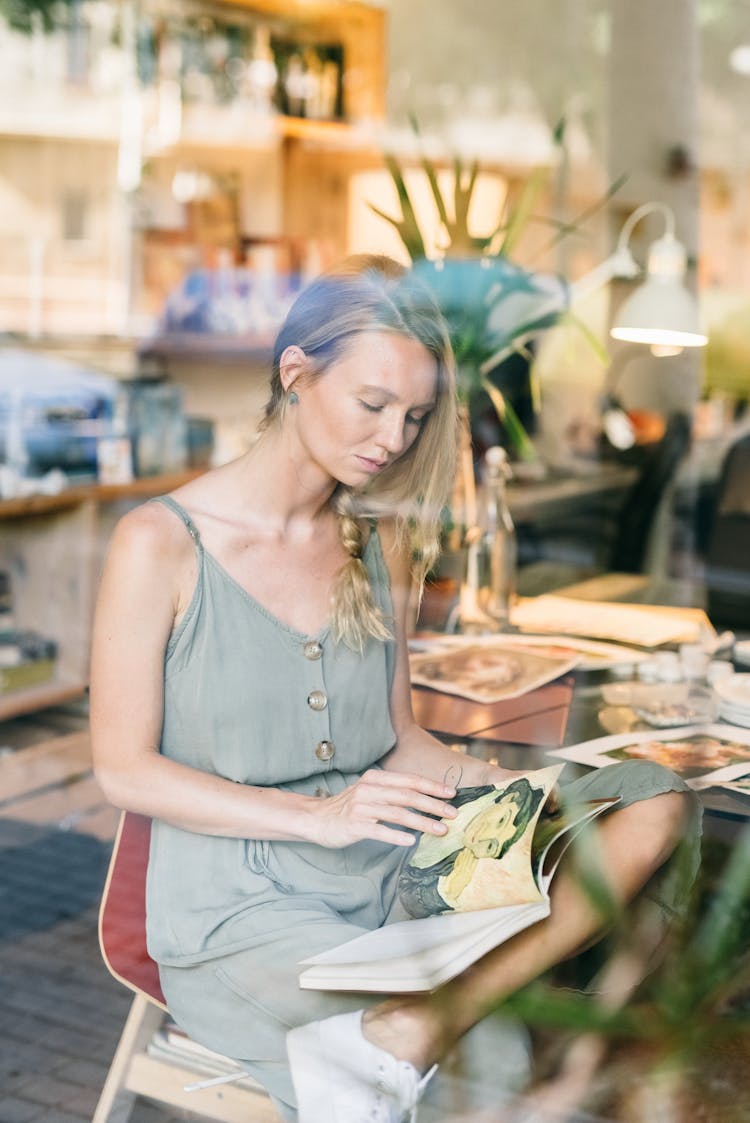 Photo Of A Woman Looking At A Painting In A Book