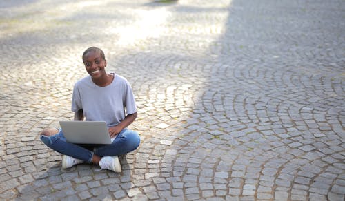 A Person Sitting on the Ground while Using a Laptop