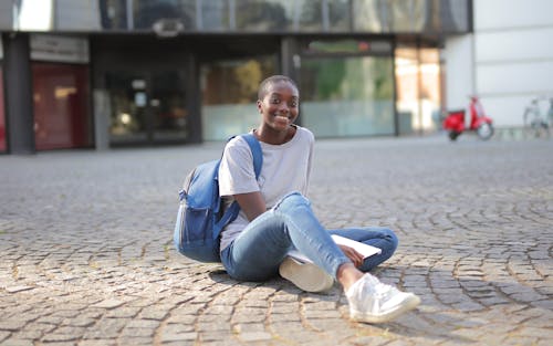 Woman in White Shirt and Blue Denim Jeans Sitting on Concrete Floor