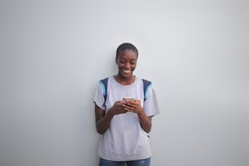 Woman in Gray Crew Neck T-shirt Using Smartphone