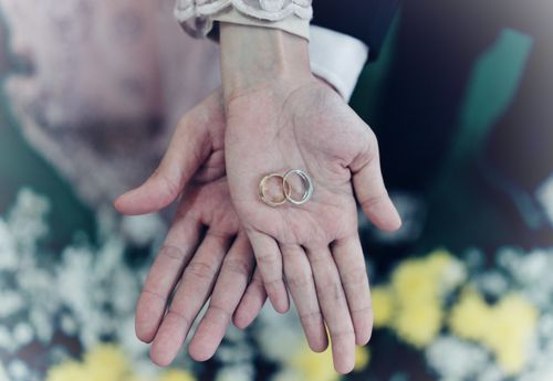 Free Romantic close-up of intertwined hands holding wedding rings, symbolizing love and commitment. Stock Photo