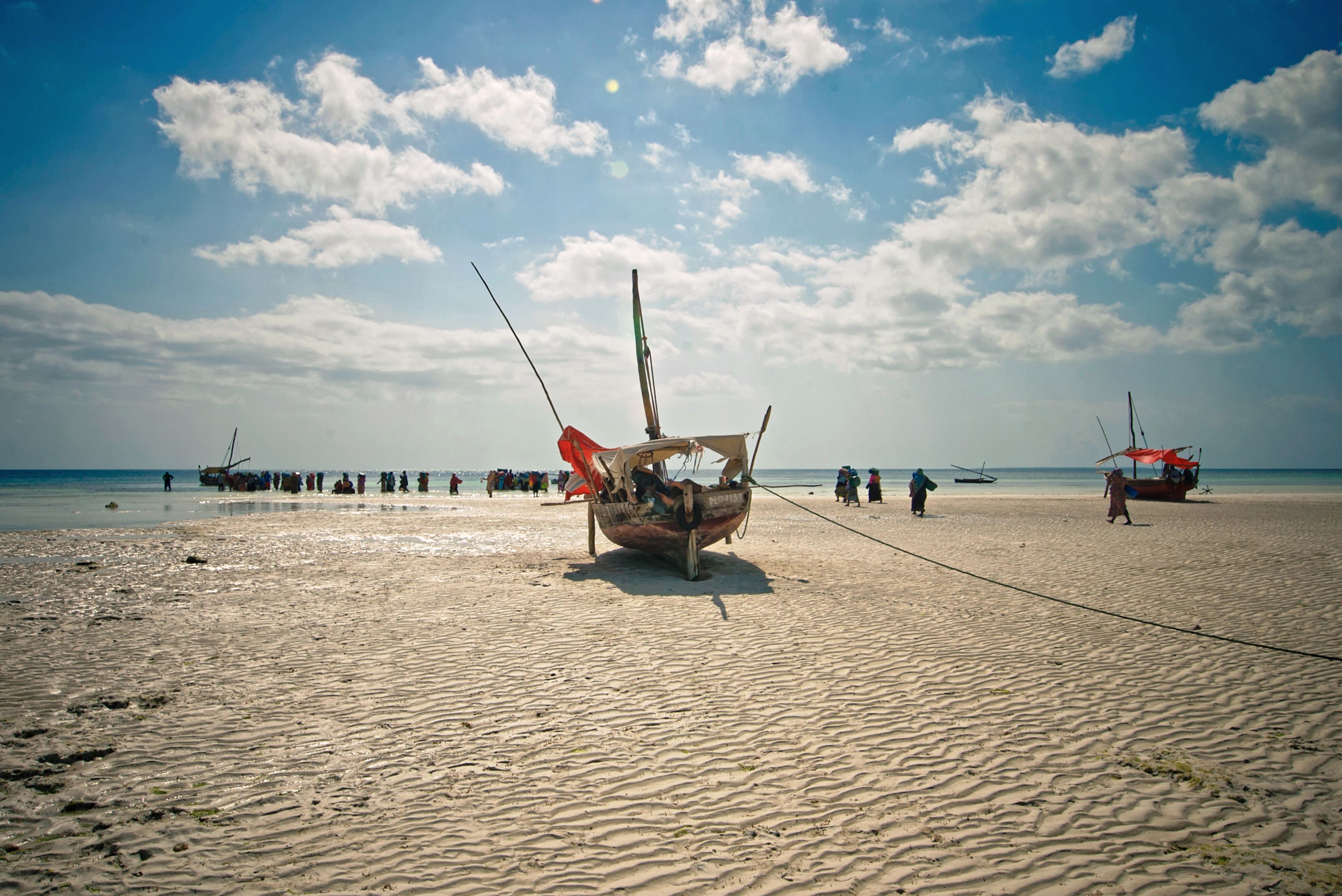 Wooden dhows resting on a sandy beach at low tide on Zanzibar's east coast