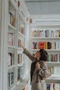 一名年轻女子伸手从时尚图书馆的书架上取下一本书，体现了教育与休闲的结合