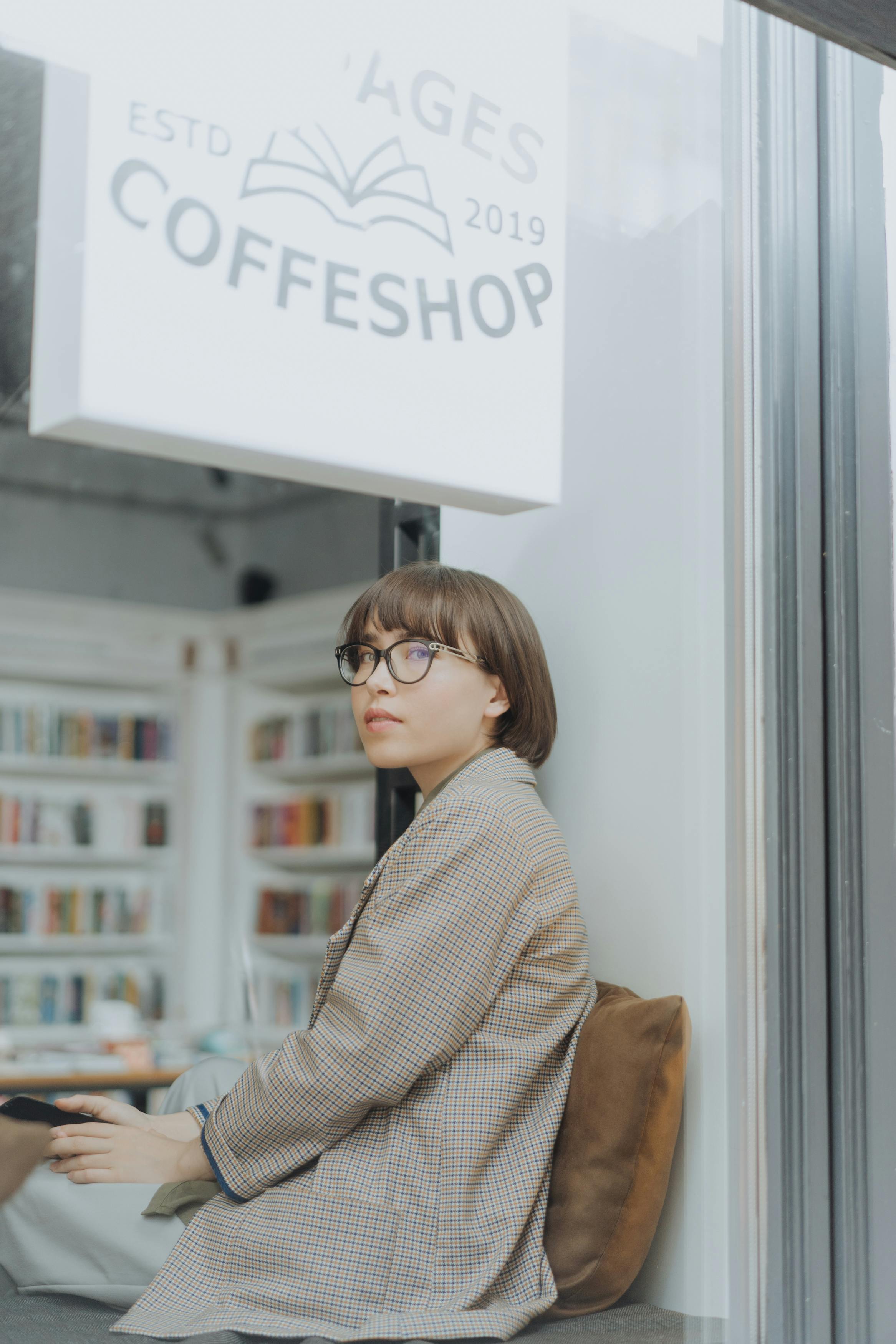 一名年轻女子坐在咖啡店的角落里，在轻松的氛围中阅读