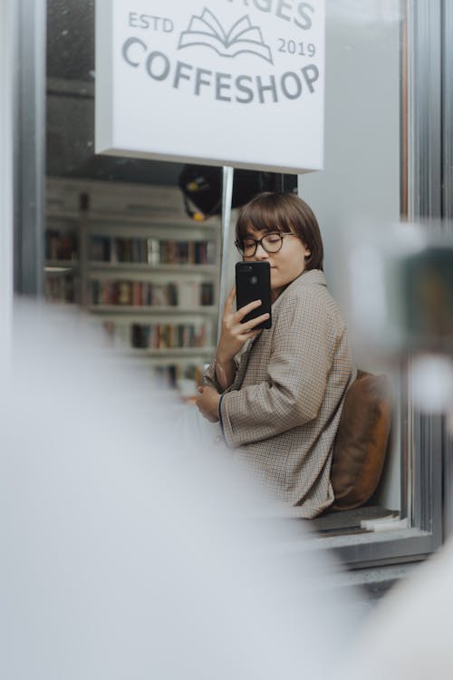 Woman in Brown Coat Holding Black Smartphone