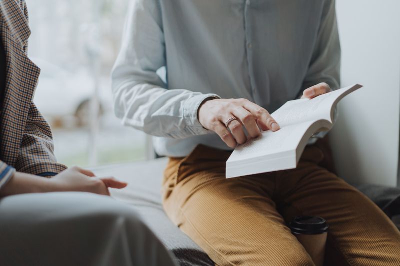 Persoană citind o carte într-un mediu confortabil, cu rafturi de cărți în fundal