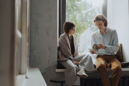 Man and Woman Sitting on Chair Beside Window