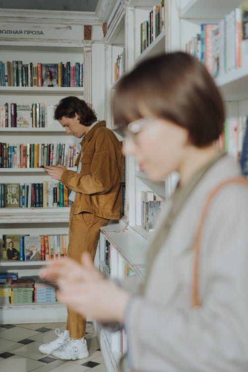 Man and Woman Kissing in Front of White Wooden Book Shelf