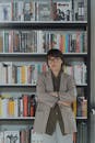 一位戴眼镜的女人双臂交叉，自信地站在图书馆里，周围都是书籍