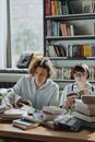 Woman in Gray Dress Shirt Sitting Beside Woman in White Long Sleeve Shirt