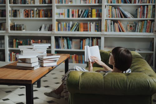 Free Girl Reading Book on Brown Wooden Table Stock Photo