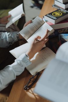 在舒适的学习环境中，一个人正一边读书，一边在笔记本上写作，周围堆满了书籍