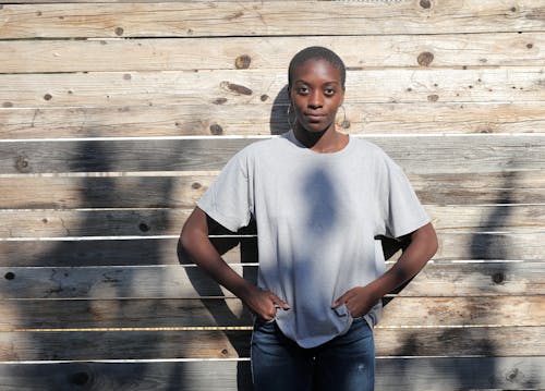 Woman in Gray Shirt Standing Beside Wooden Panel