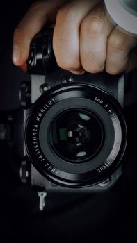 Close-up of a digital camera lens held by a person emphasizing photography equipment.