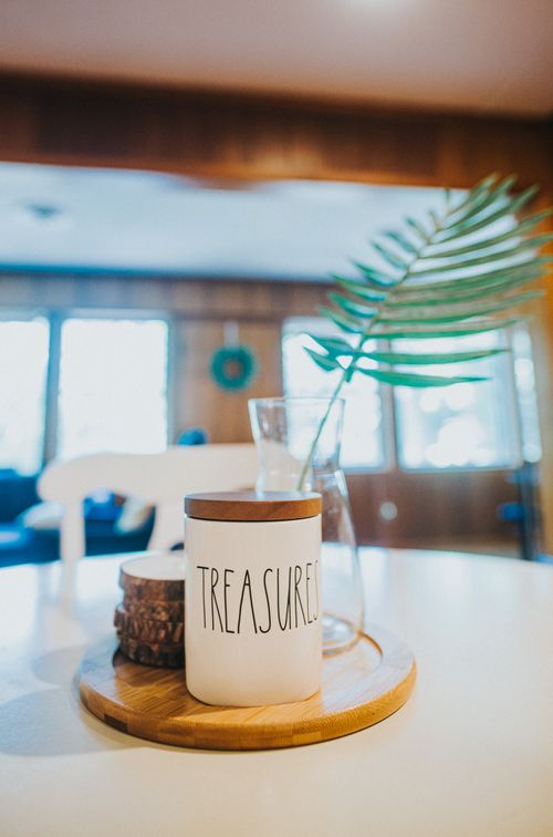 Free Arrangement of white ceramic sugar bowl with word Treasures placed near green plant twig in glass vase on round dining table Stock Photo