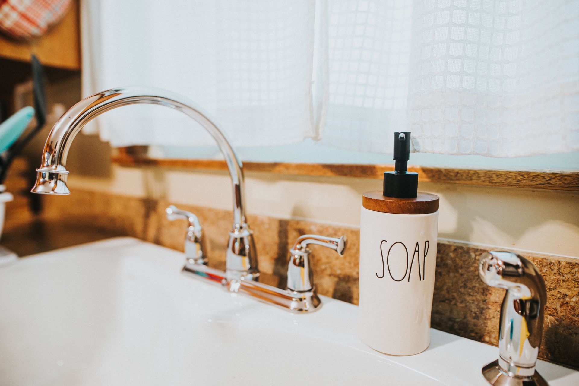 Liquid soap dispenser placed on sink in kitchen
