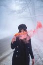 A Woman Wearing a Black Coat while Holding a Smoke Bomb